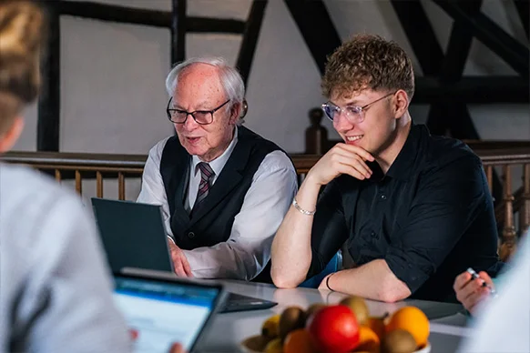 Zwei Teammitglieder im Gespräch am Laptop – Erfahrung trifft frische Perspektive